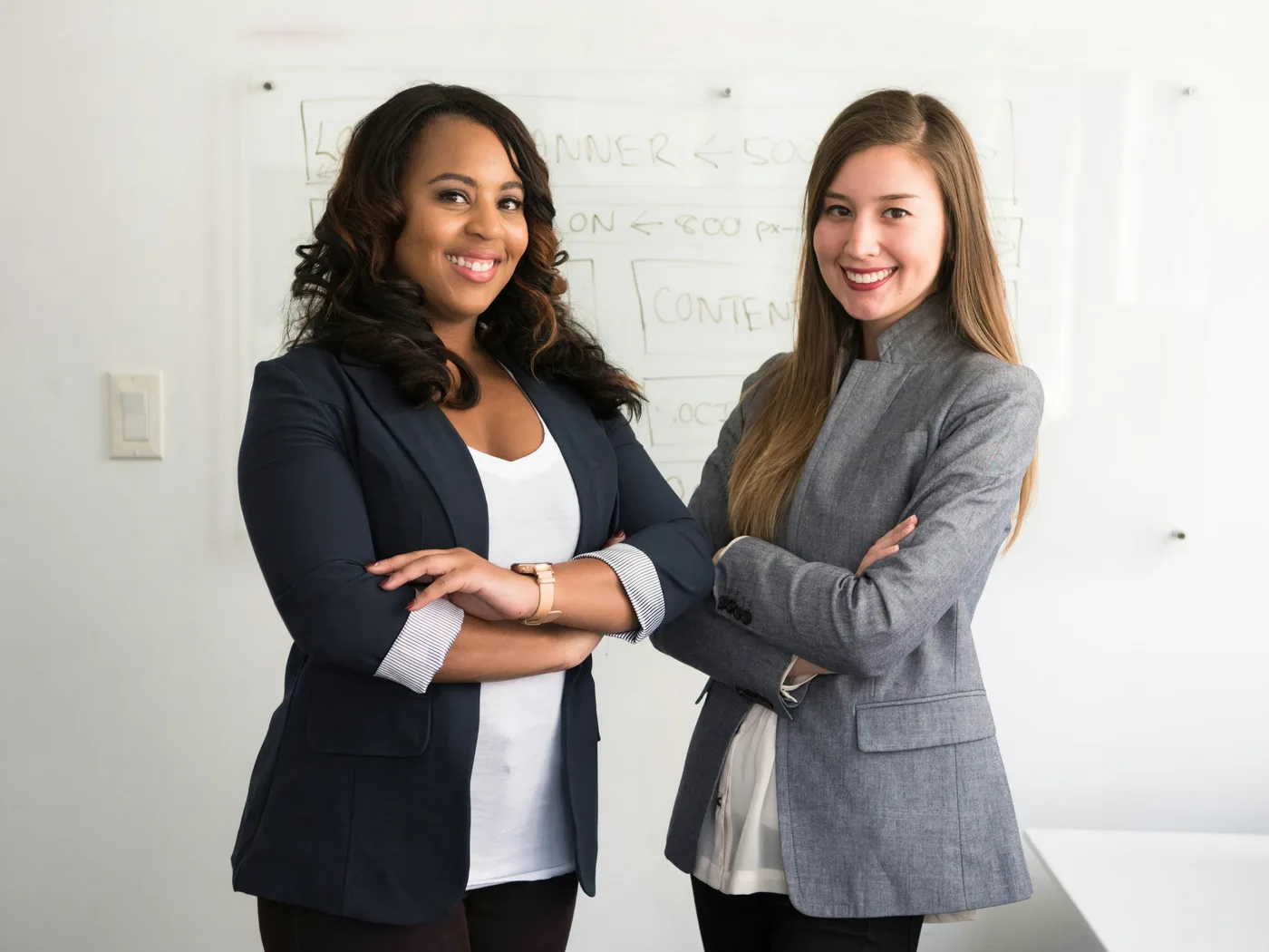 Two professional women standing confidently in a strategy and planning environment